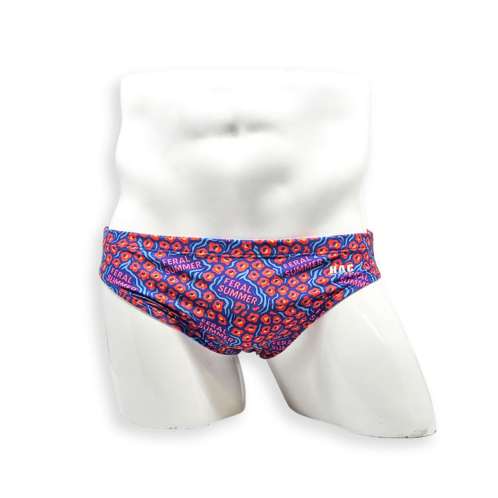 Front view of men’s Flat Front swim brief in HAC Swim’s Feral Summer print featuring electric blue, hot pink lettering and orange abstract pattern.