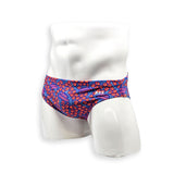 Hero view of men’s Flat Front swim brief in HAC Swim’s Feral Summer print featuring electric blue, hot pink lettering and orange abstract pattern.